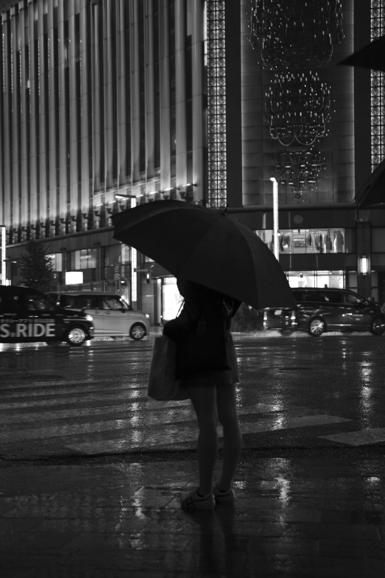 雨の銀座で大きな傘を差して立つ人物