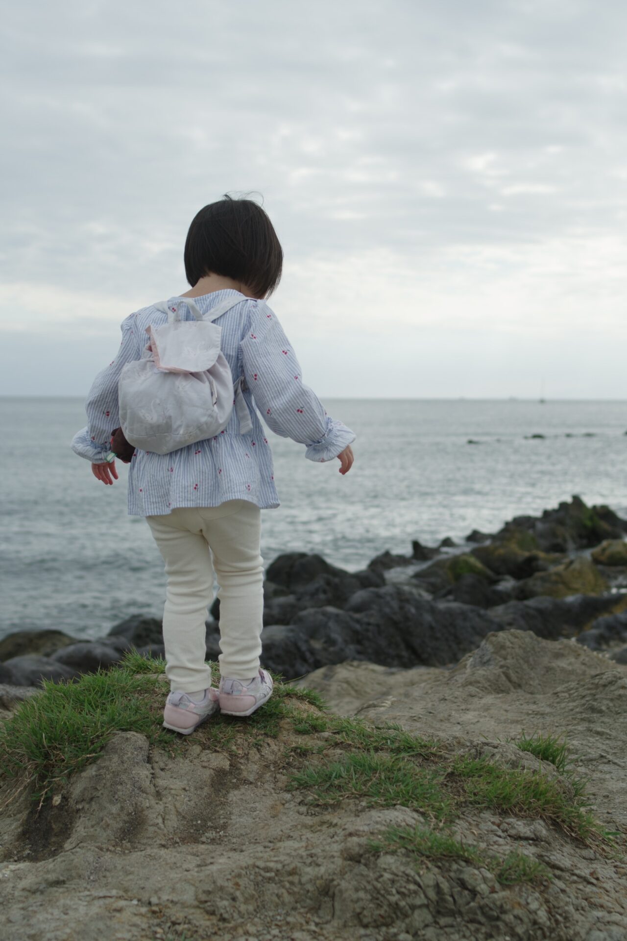 一色海岸の岩場に立つ娘。PENTAX K-3 Mark IIIとFA31mm Limitedで撮影。