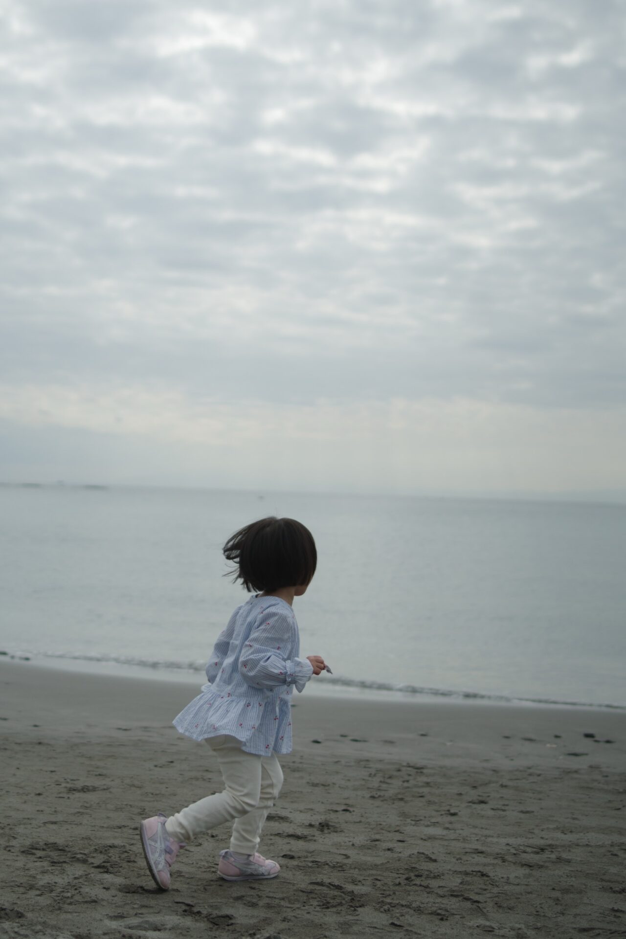 一色海岸の波打ち際を走る娘。曇り空の下、PENTAX K-3 Mark IIIとFA31mm Limitedで撮影。