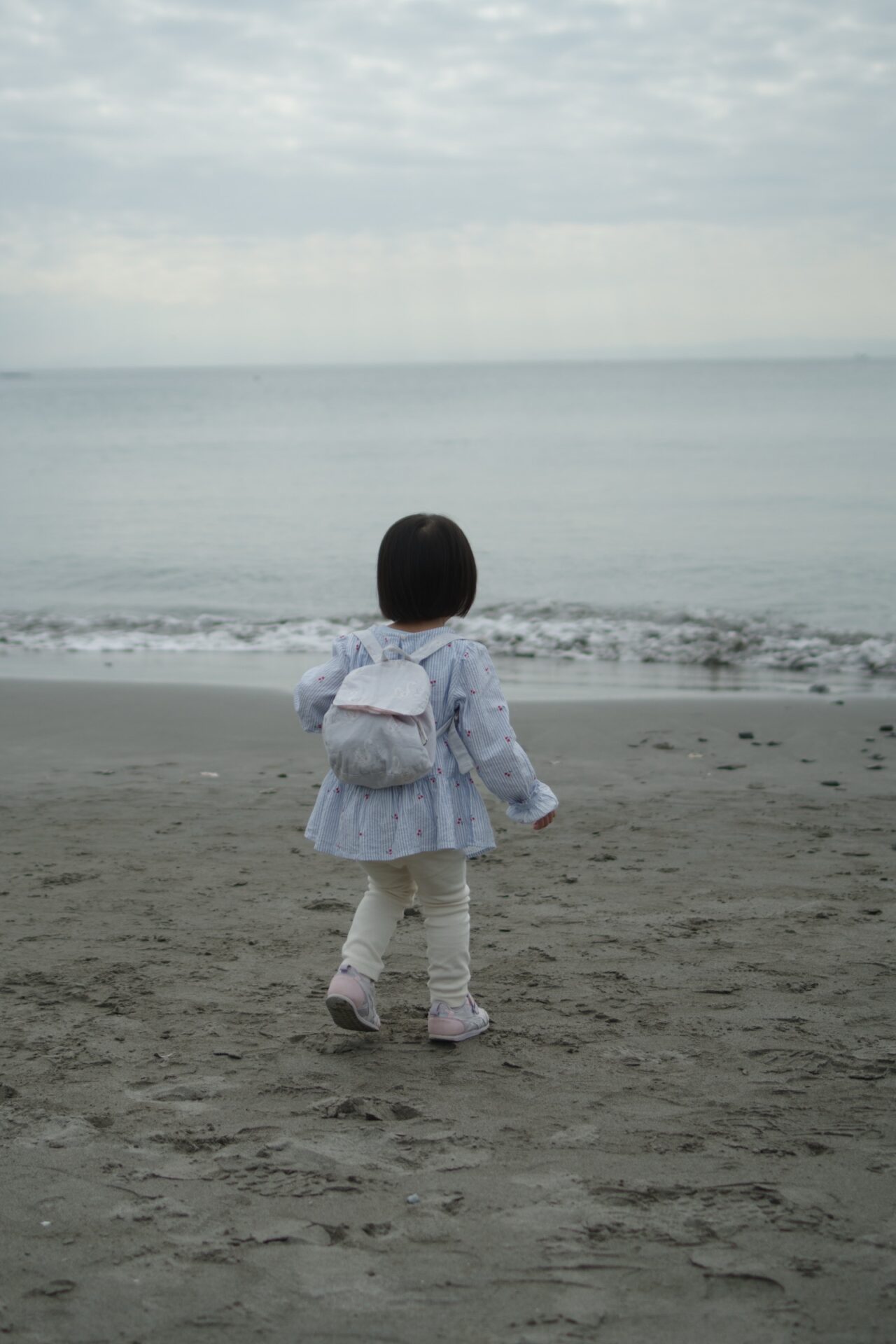 一色海岸の砂浜から海へ向かって歩く娘。PENTAX K-3 Mark IIIとFA31mm Limitedで撮影。
